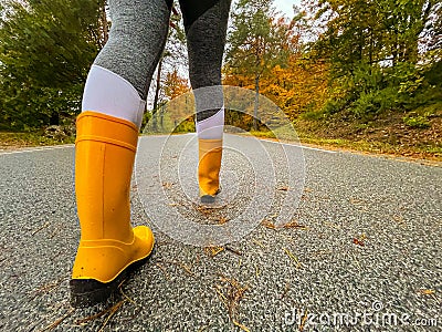 CLOSE UP: Female traveler wears rubber boots while walking down a forest route Stock Photo