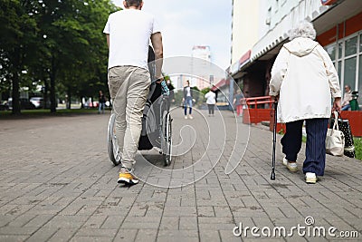 Man driving disabled woman in wheelchair across street, walking, shopping Editorial Stock Photo