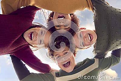 Low Angle Portrait Of Children Having Fun Playing Outdoors Linking Arms Looking Down Into Camera Stock Photo