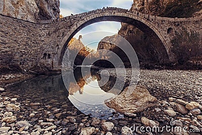 Low angle shot of a beautiful stone arch bridge in Zagori, Greece with a pile of water underneath it Stock Photo