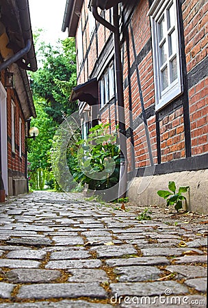 Low angle shot to a historical cobblestone alley with red half-timbered houses Stock Photo