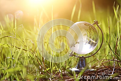 low angle small crystal globe in the grass. travel and global issues concept. Stock Photo