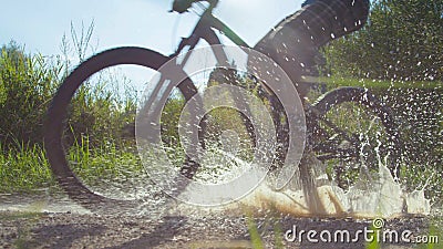 LOW ANGLE: Unrecognizable active person rides their bike into a muddy puddle. Stock Photo
