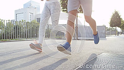 LOW ANGLE: Unrecognizable sporty couple running on a sunny morning in the city Stock Photo