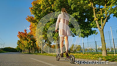 LOW ANGLE: Unrecognizable young woman in high heels rides an e-scooter to work. Stock Photo