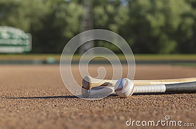 Low angle view of a baseball and bats on dirt infield of baseball park in afternoon sunlight Stock Photo