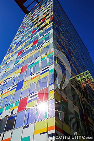 Low angle view beyond colorful skyscraper facade with windows against dark blue clear cloudless sky, sunburst effect Editorial Stock Photo
