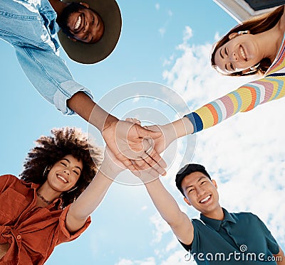 Low angle view of diverse group of people standing huddled together with hands piled in the middle. African American Stock Photo