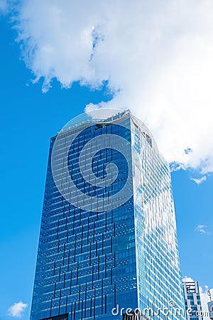 Low angle view exterior of high modern tower building office structure with glass window reflection and blue sky white clouds Stock Photo