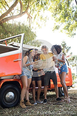 Low angle view of friends looking at map at campsite Stock Photo