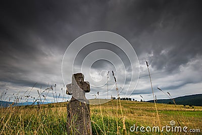 Low angle view of a hand carved old stone cross , dramatic stormclouds Stock Photo