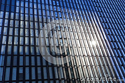 Low angle view on isolated skyscraper facade with monochrome geometrical windows pattern and sun burst effect from sunshine Editorial Stock Photo