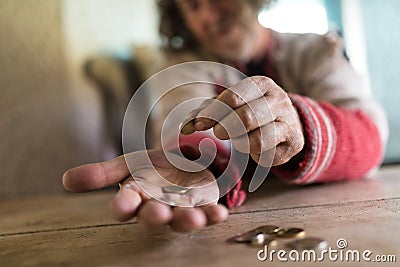 Low angle view of an old man in torn sweater counting Euro coins Stock Photo