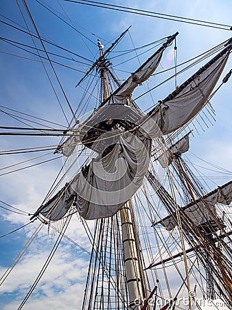 Old Tall Ship Sail, Mast, and Riggings Against Blue Sky Stock Photo