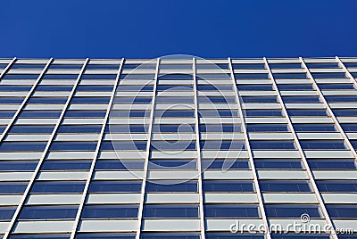 Low angle view on skyscraper facade with geometric symmetrical pattern lines against deep blue cloudless sky Editorial Stock Photo