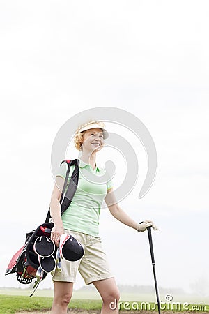 Low angle view of smiling female golfer standing against clear sky Stock Photo