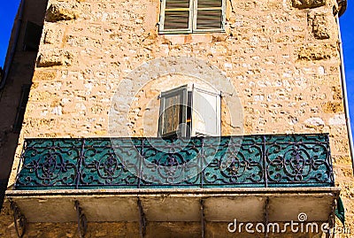 Low angle view on stone facade of typical French house and balcony with ancient ornate lattice work - Castellane, France Stock Photo