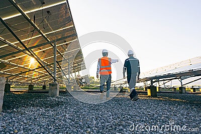 Low angle view of technician walks with investor through field of solar panels, Alternative energy to conserve the world`s energy Stock Photo