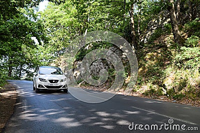 Low angle view of a white Seat Ibiza car driving on forest road. Editorial Stock Photo