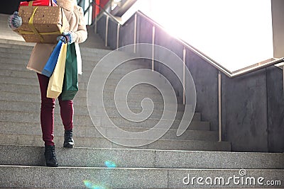 Low angle view of woman with gifts and shopping bags moving down steps Stock Photo