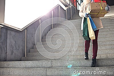 Low angle view of woman with gifts and shopping bags moving down steps Stock Photo