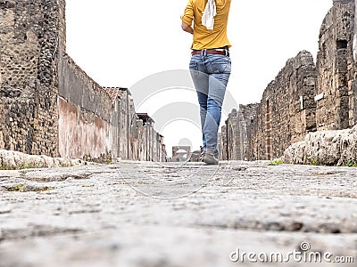 Low angle view of a woman in yellow clothes walking while exploring ancient ruins Stock Photo