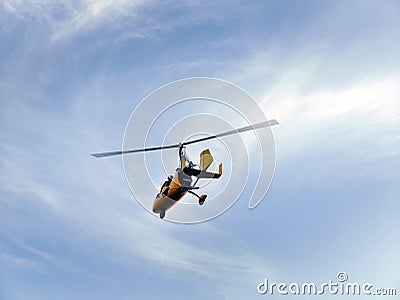 Low angle view of yellow color Gyrocopter flying in the blue sky and dramatic clouds, fun fly, aero sports, skydive, Roto craft, Stock Photo