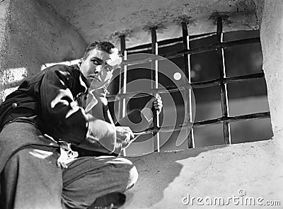 Low angle view of a young man trying to escape from a prison cell Stock Photo