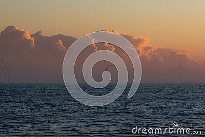 Low bank of misty cloud behind offshore wind turbines. Spiritual landscape Stock Photo