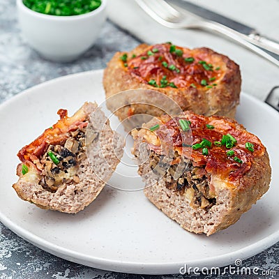 Low carb paleo meat cups, stuffed with champignons, bacon and cheese, garnished with green onion, on plate, square format Stock Photo