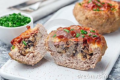 Low carb paleo meat cups, stuffed with champignons, bacon and cheese, garnished with green onion, on a white plate, horizontal Stock Photo