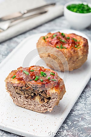 Low carb paleo meat cups, stuffed with champignons, bacon and cheese, garnished with green onion, on white plate, vertical Stock Photo