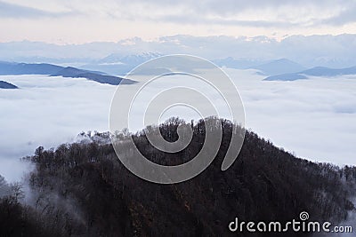 Low clouds, view of winter forest and mountains from observation deck, horizontal picture of amazing natural phenomenon. Beautiful Stock Photo