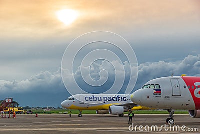 Low cost airlines Cebu Pacific and Air Asia aircraft at colorful sunset at Puerta Princesa Airport in Palawan island Editorial Stock Photo