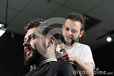 Low fade machine haircut for handsome bearded man in barbershop. Hair cut with a smooth transition. Stock Photo