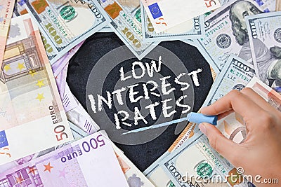 Low interest rate at mortgage loans, credit card or other types of loans, text in heart shape from cash banknotes in various curre Stock Photo