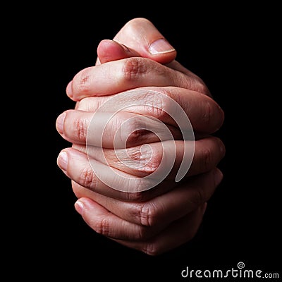 Low key, close up of hands of a faithful mature man praying, hands folded, interlaced fingers in worship to god Stock Photo