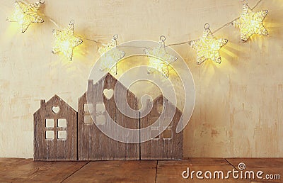 Low key image of vintage wooden house decor on wooden table and stars garland. retro filtered. selective focus Stock Photo