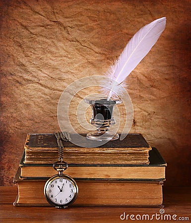 Low key image of white Feather, inkwell and ancient books on old wooden table. Stock Photo