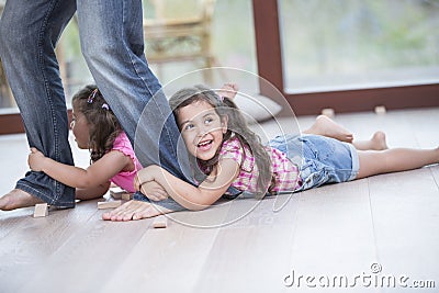Low section of father dragging girls on hardwood floor Stock Photo