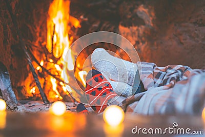 Low section legs of husband and wife covered in socks and warm blanket relaxing in front of burning fireplace during winter Stock Photo