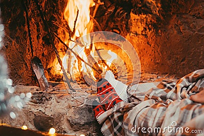 Low section legs of husband and wife covered in socks and warm blanket relaxing in front of burning fireplace during winter Stock Photo