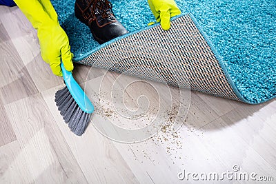 Janitor Sweeping Dirt Under The Carpet Stock Photo