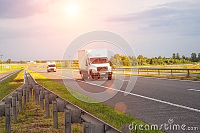 A low-tonnage commercial refrigerated van transports perishable products in the summer on a country road against the Stock Photo
