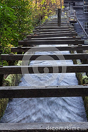 Low view of a wood walled sluice channeling water toward an old mill Stock Photo