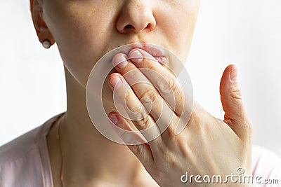 Lower part part of woman face with Red bubbles of virus herpes on her lips, she hides with her palm on white background, Zoster, Stock Photo