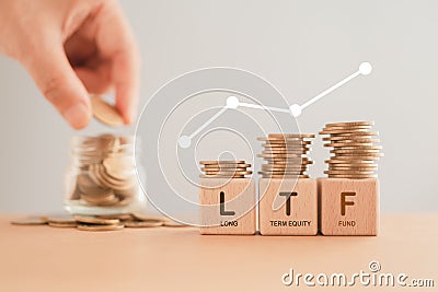 LTF ,Long Term Equity Fund, on wooden cube blocks and stack of coins with blurred hand and coins in jar, for business Stock Photo