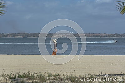 Luanda/Angola - 11 11 2018: View at the beach on Mussulo Island, with a woman walking, water with a boat jet, Luanda city and the Editorial Stock Photo