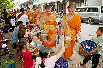 Monks collect alms and offerings during daily early morning procession in Luang Prabang, Laos. Editorial Stock Photo