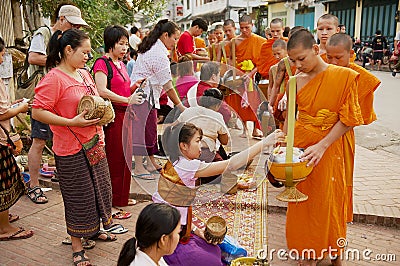 Monks collect alms and offerings during daily early morning procession in Luang Prabang, Laos. Editorial Stock Photo